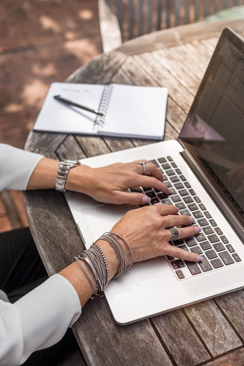 typing on laptop person typing on MacBook Pro on brown wooden table during daytime photo
